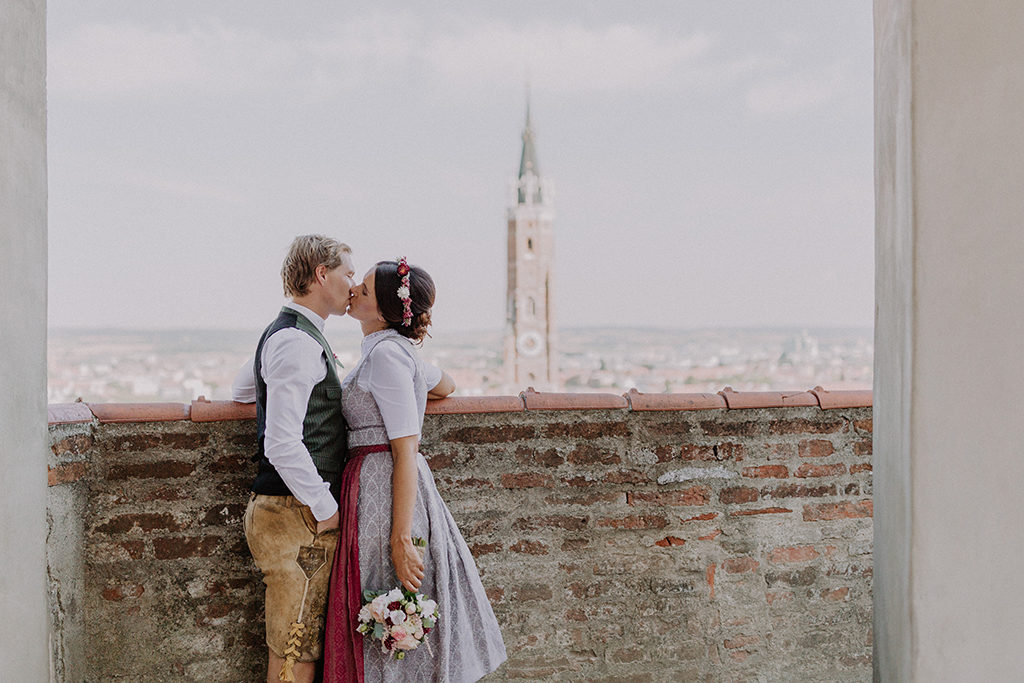 Brautpaar küsst sich vor der Kulisse der Stadt und der Martinskirche in Landshut auf der Burg Trausnitz