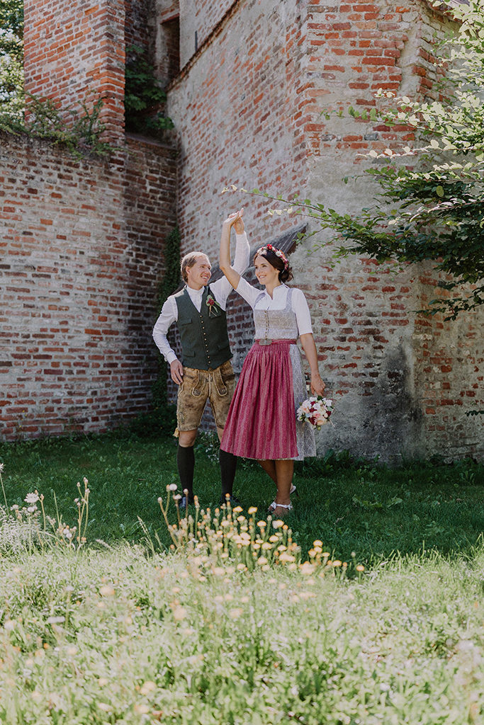 Das Brautpaar tanzt vor alten Steinmauer auf der Burg Trausnitz