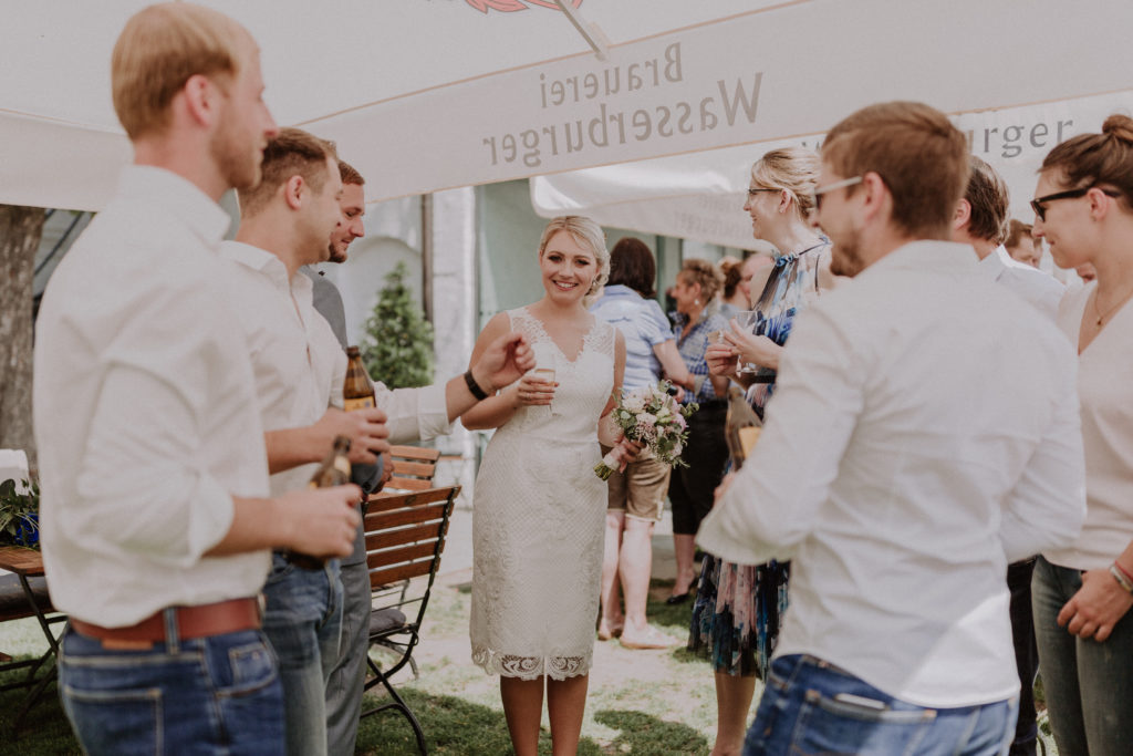 Braut lacht glücklich inmitten von den Hochzeitsgästen