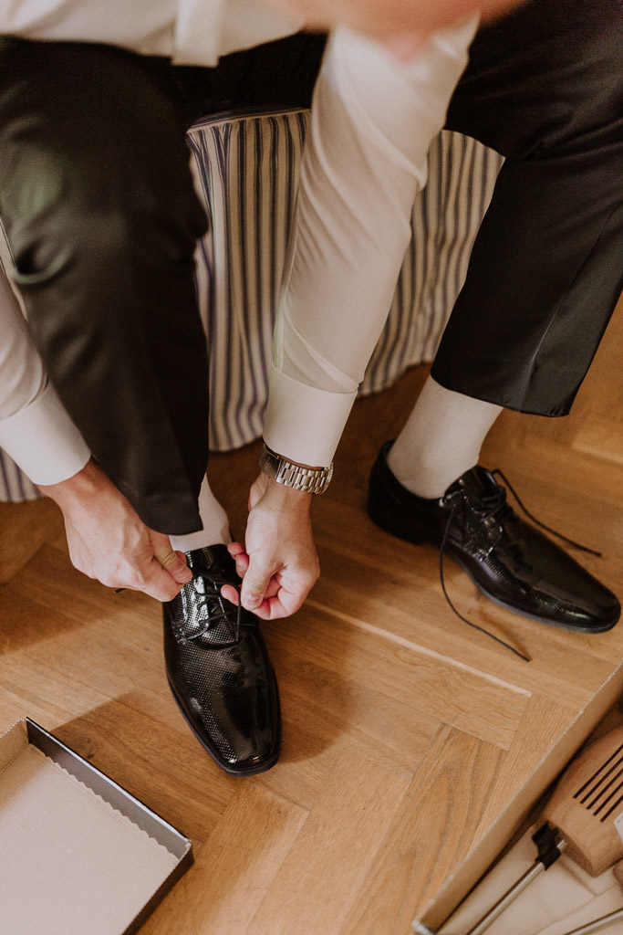 Bräutigam zieht seine Schuhe im Hotelzimmer im Schloss an