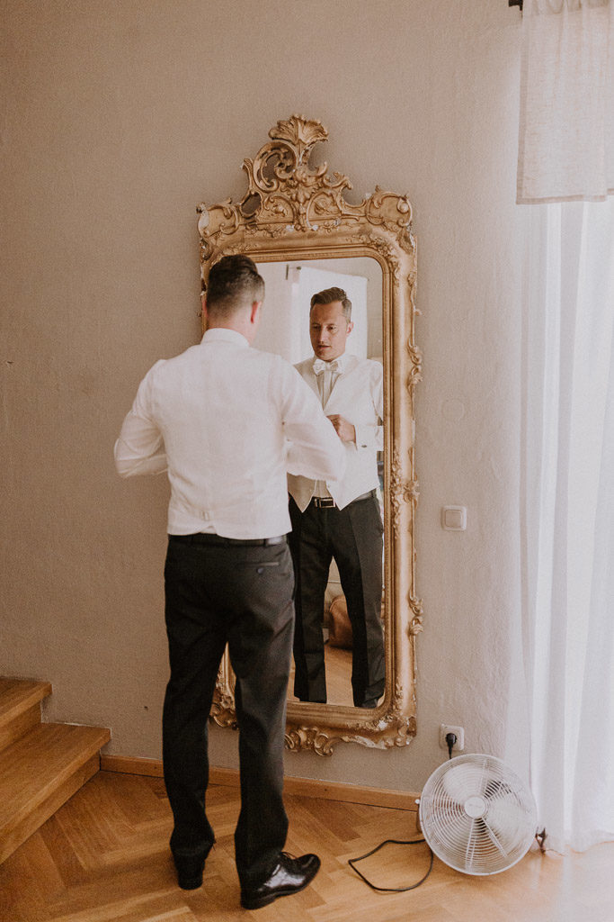 Bräutigam vor Spiegel im Hotelzimmer des Schlosses